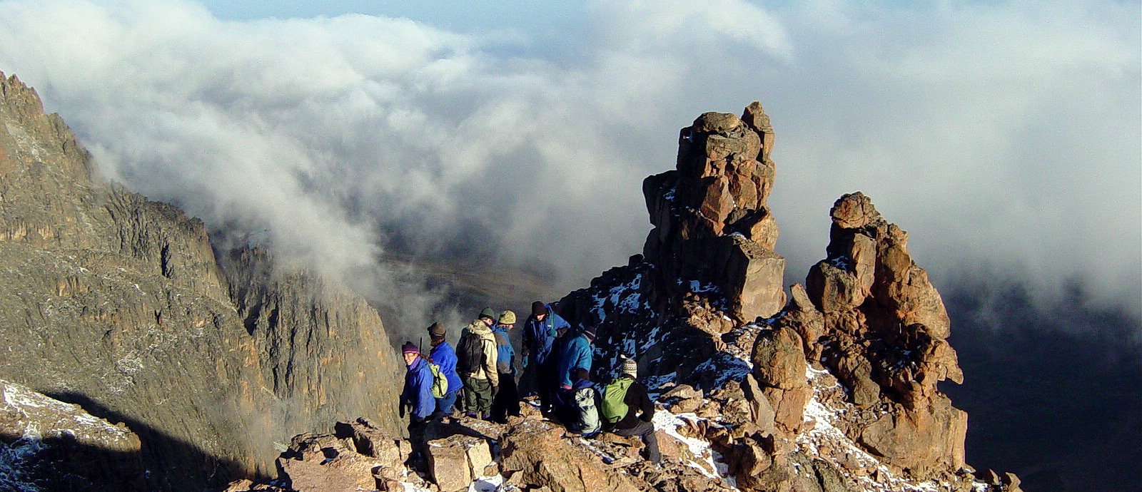 Hikers on the rocky summit ridge of Mount Kenya above the clouds